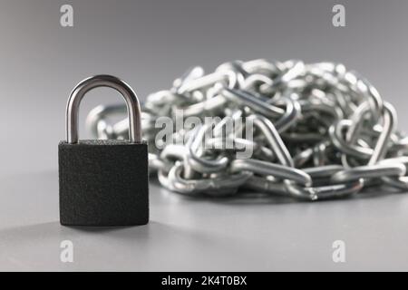 Padlock and metal chains on a gray background Stock Photo
