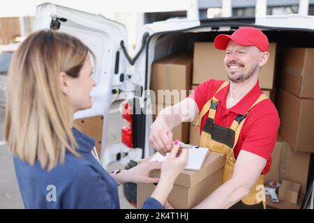 A woman on the street receives a package from a courier Stock Photo