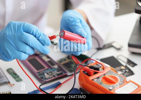 Hands hold a red lithium titanium battery and a voltmeter Stock Photo