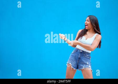 Copy space photo of Latin young woman pulling a sign of sales, hiring, isolated in a blue background Stock Photo