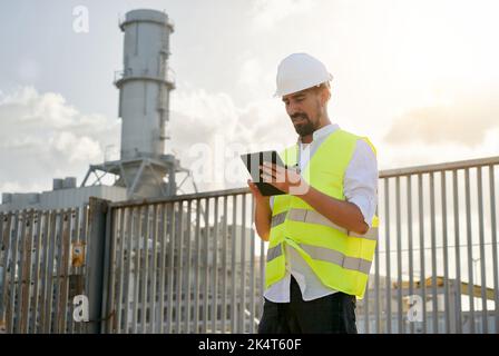 Photo of caucasian man engineer using digital table to do inspections at energy generator plant. Stock Photo