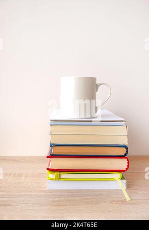 Stack of hardcover books with a white cup of coffee on the top. Stock Photo