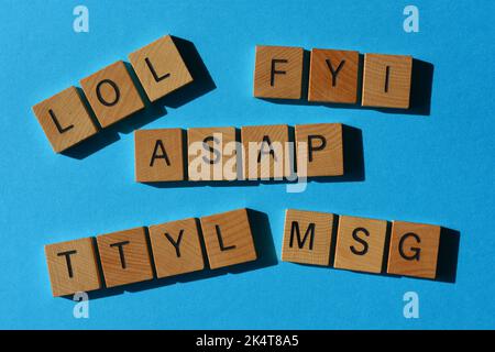 LOL, FYI, ASAP, TTYL, MSG, acronyms used in text speak in wooden alphabet letters isolated on blue background Stock Photo