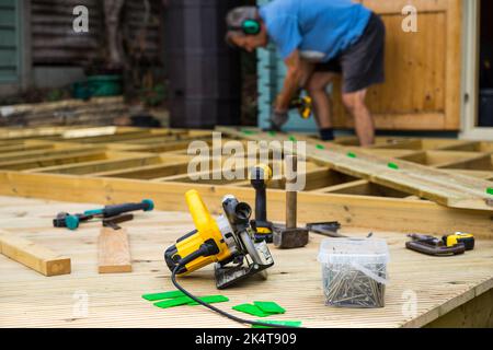 Man constructing a deck, showing decking joists, planks and deck tools Stock Photo