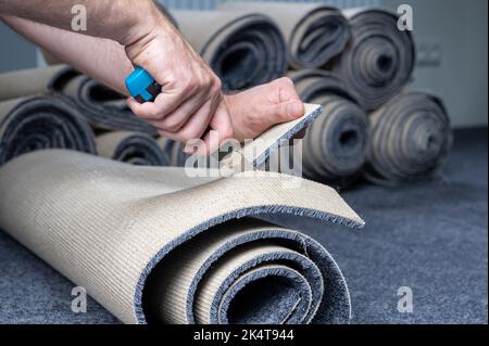 Handyman cutting a new carpet with a carpet cutter. Stock Photo