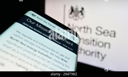 Smartphone with webpage of British North Sea Transition Authority (NSTA) on screen in front of logo. Focus on top-left of phone display. Stock Photo