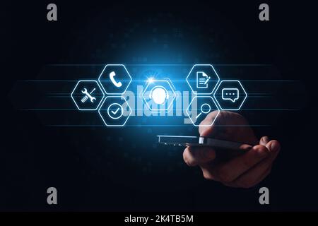 The concept of remote support and assistance for customer service. Person holding smartphone with hologram Stock Photo