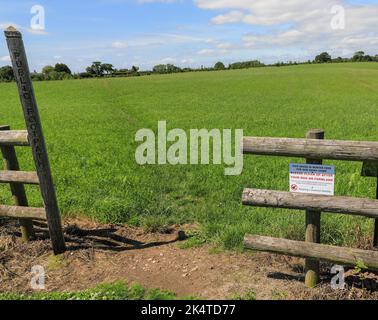 A sign on a public footpath through a field of winter feed for cows saying 'please clean up after your dog' due to a parasite called Neospora, England Stock Photo