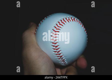 Baseball ball in hand close up on black background Stock Photo