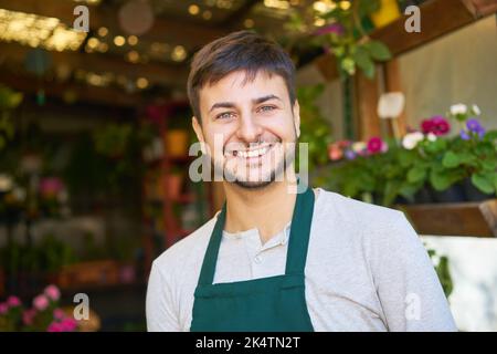 Young man as florist and happy startup founder in flower shop or nursery Stock Photo