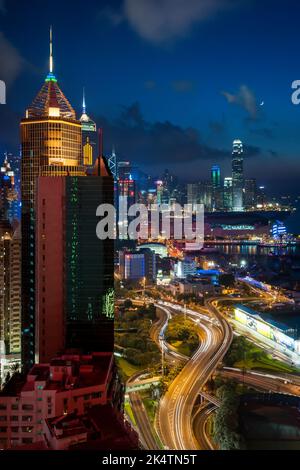 The high-rise commercial buildings of Causeway Bay, Wan Chai and Central, Hong Kong Island, at dusk with a new moon and light trails from cars, 2011 Stock Photo