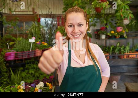 Proud florist giving thumbs up for good quality at nursery flower shop Stock Photo