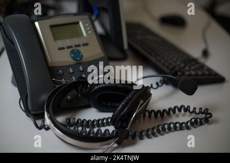 Stationary phone and headset on desk indoors, closeup. Communication support, call center and customer support service. Stock Photo