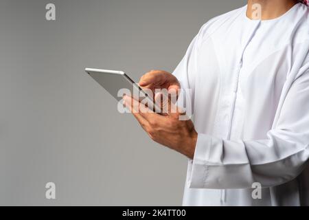 Close up of Arab man holding digital tablet on gray background Stock Photo