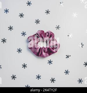 One purple velvet scrunchy and silver snowflakes on gray background. Winter trends and hairstyles concept Stock Photo