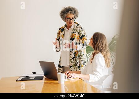 Two diverse businesswomen having a discussion in a modern meeting room. Creative businesswomen collaborating on a new task in a woman-owned startup. Stock Photo
