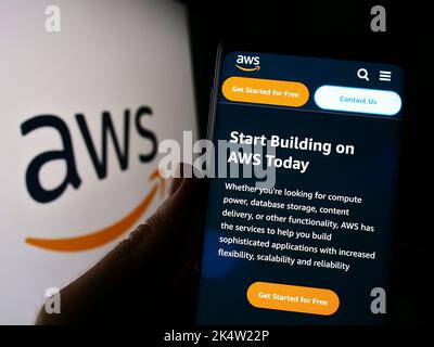 Person holding cellphone with website of US cloud company Amazon Web Services Inc. (AWS) on screen with logo. Focus on center of phone display. Stock Photo