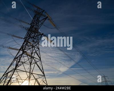 I love electricity pylons; I find their abstract, gaunt shapes endlessly fascinating. Here we see two giant pylons in a field by the Thames at Kenning Stock Photo