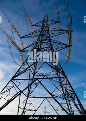 I love electricity pylons; I find their abstract, gaunt shapes endlessly fascinating. Here we see two giant pylons in a field by the Thames at Kenning Stock Photo