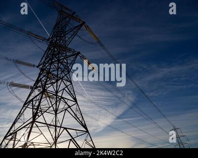 I love electricity pylons; I find their abstract, gaunt shapes endlessly fascinating. Here we see two giant pylons in a field by the Thames at Kenning Stock Photo