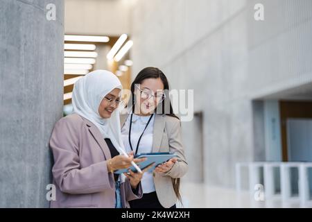 Two female co-workers using tablet in an office building Stock Photo
