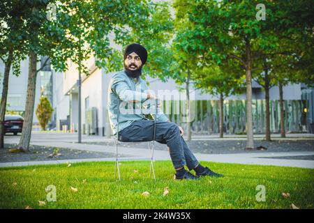 A South Asian male sitting on a chair in a garden Stock Photo