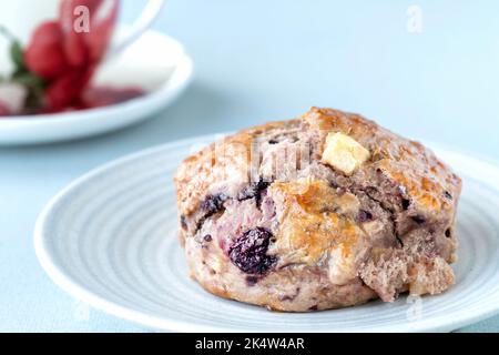 Fresh home made apple and blackberry scones, served plated with a cup of tea in a china cup. Cooked from a national trust recipe book Stock Photo