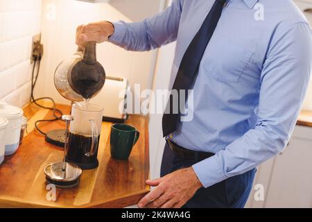 Midsection of caucasian man standing in kitchen and preparing coffee Stock Photo
