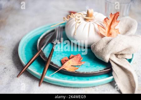 Autumnal place setting with a decorative ceramic pumpkin and autumn leaves Stock Photo