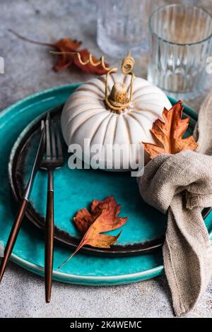 Autumnal place setting with a decorative ceramic pumpkin and autumn leaves Stock Photo