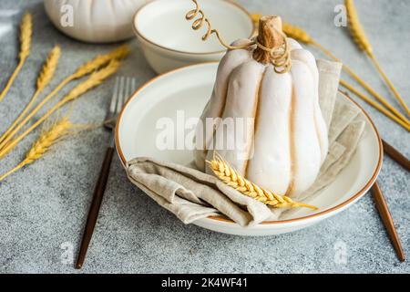 Autumnal place setting with ears of wheat and a decorative ceramic pumpkin Stock Photo