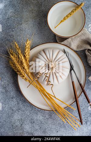Overhead view of an autumnal place setting with ears of wheat and a decorative ceramic pumpkin Stock Photo