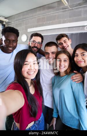 Vertical photo of a multiracial group of friends taking a selfie - New concept of normal friendship with young people looking at the camera and Stock Photo