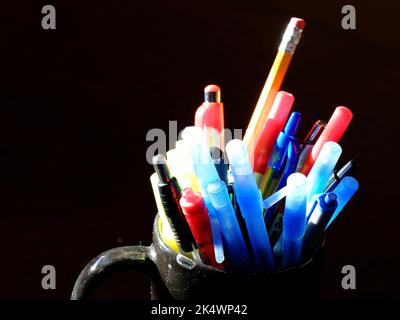 Several pens and pencils in mug on desk for work or education Stock Photo