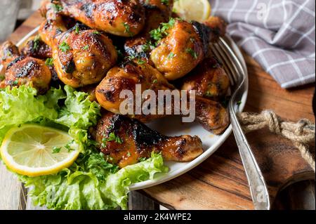 Plate with chicken drumsticks on wooden cutting board Stock Photo