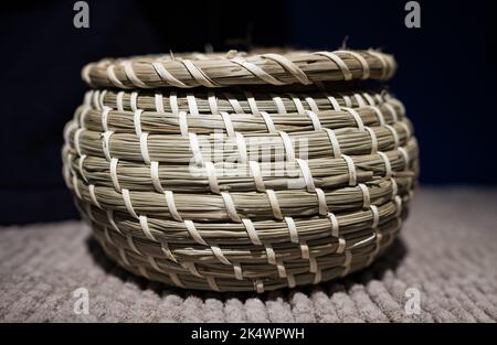 Handmade wicker picnic basket in the dark background. Wicker basket with lid. Wicker storage basket. Nobody, selective focus Stock Photo