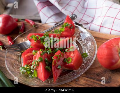 Beef tomato salad with chives and olive oil on a plate Stock Photo