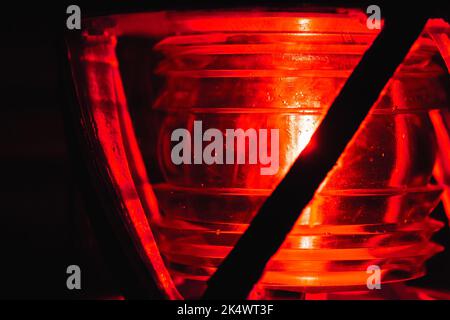 Red lamp glows in metal frame on a top of a lighthouse, close up photo with selective soft focus Stock Photo