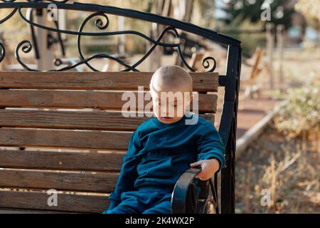 Cute blond boy with down syndrome walks in the park Stock Photo