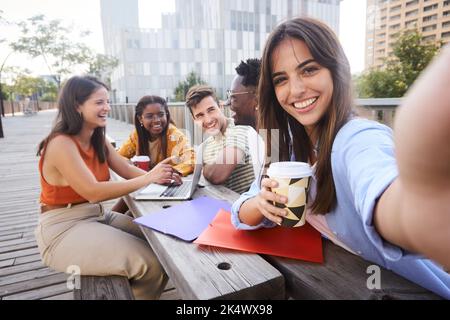 Happy selfie of a beautiful white lady at university campus gathering with colleagues at break-time. Stock Photo