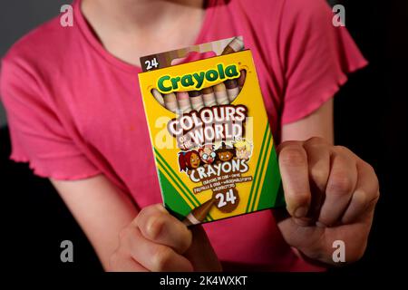 A young girl playing with some Crayola Colours of the World Book and Crayons in Chichester, West Sussex, UK. Stock Photo