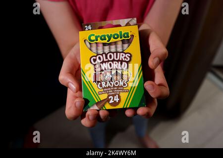 A young girl playing with some Crayola Colours of the World Book and Crayons in Chichester, West Sussex, UK. Stock Photo