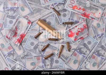 blood money of war. Cartridges with blood in dollar bills. Stock Photo