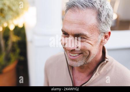 Happy caucasian man standing outside house and looking away Stock Photo