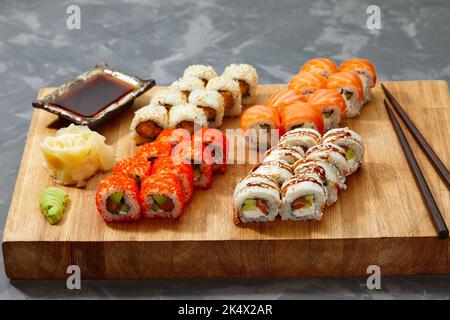 Different types of delicious and juicy sushi and rolls on a wooden board Stock Photo