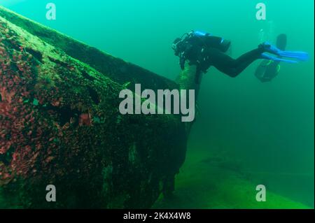 SCUBA divers exploring a mysterious sunken helicopter Stock Photo