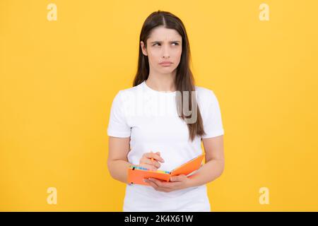 Portrait of a pensive young girl making notes. Student education in high school university college concept. Stock Photo