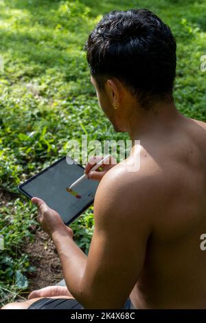 young man explaining drawing on his tablet, while teaching chakra, yoga and meditation class, mexico Stock Photo