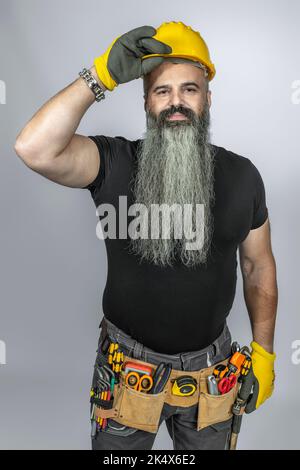 worker with tool belt greets getting up his helmet Stock Photo