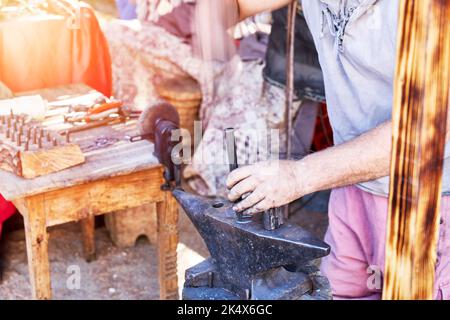 Blacksmith working on a horseshoe on top of an anvil in the open air. traditional work Stock Photo